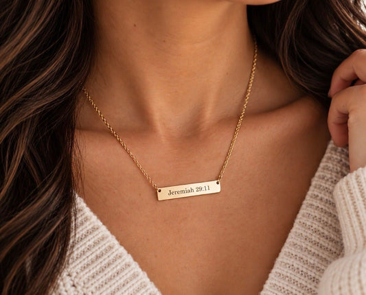 Woman wearing a gold Jeremiah 29:11 bar necklace with a cream knit sweater