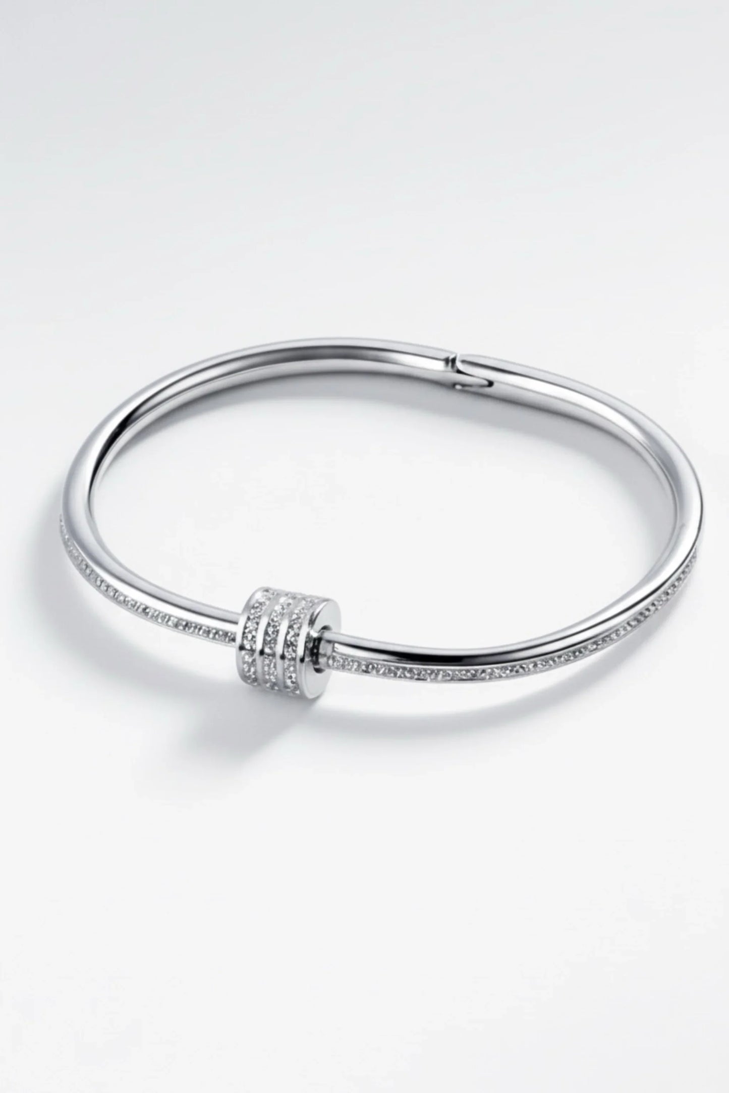 Elegant silver bangle bracelet with three rows of small sparkling diamonds on a white background