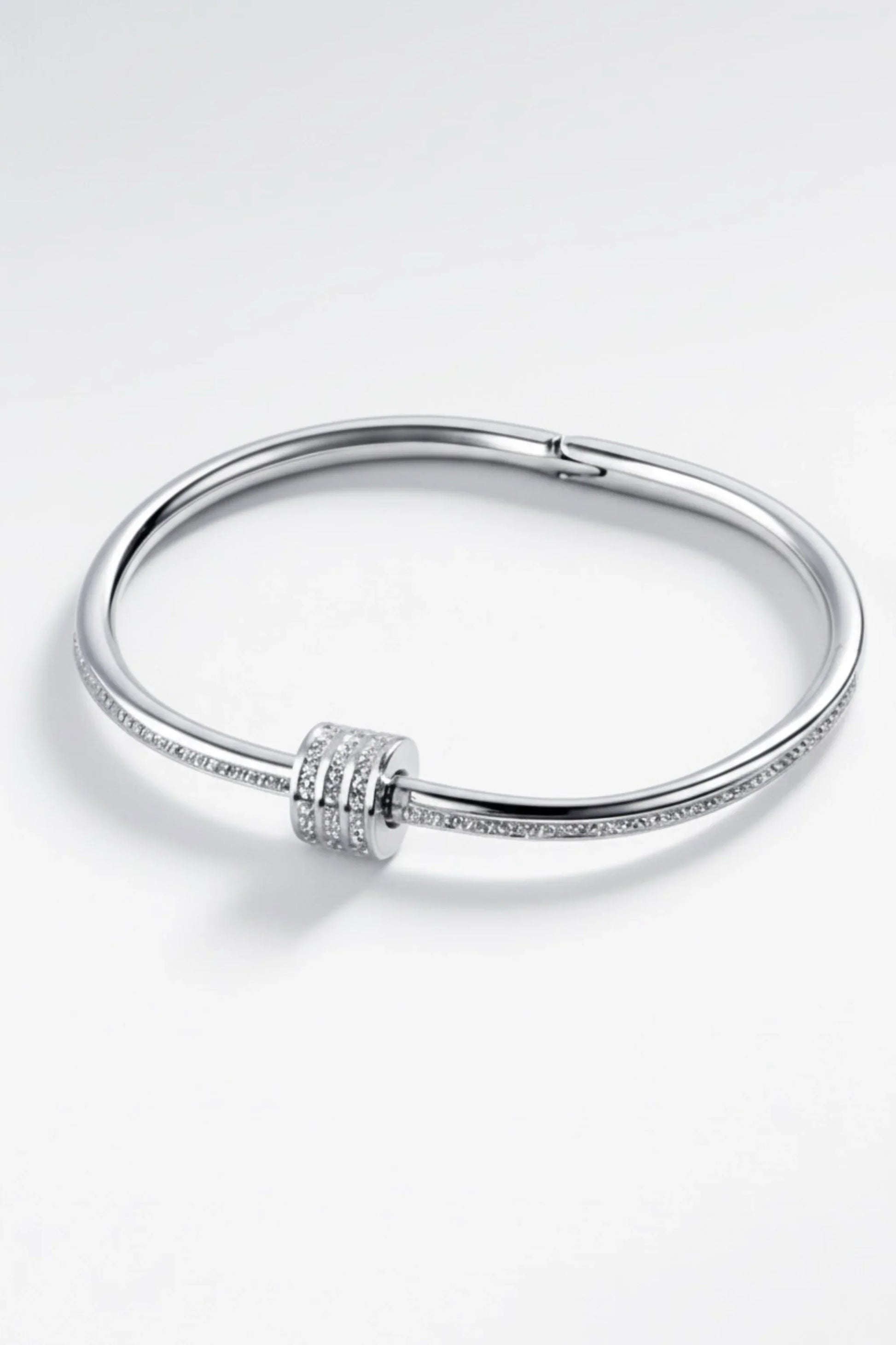 Elegant silver bangle bracelet with three rows of small sparkling diamonds on a white background