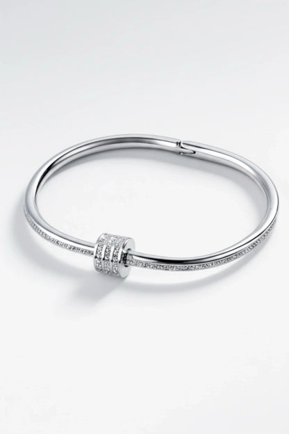 Elegant silver bangle bracelet with three rows of small sparkling diamonds on a white background