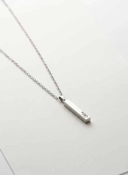 silver vertical bar pendant necklace with engraved name on silver chain on white background