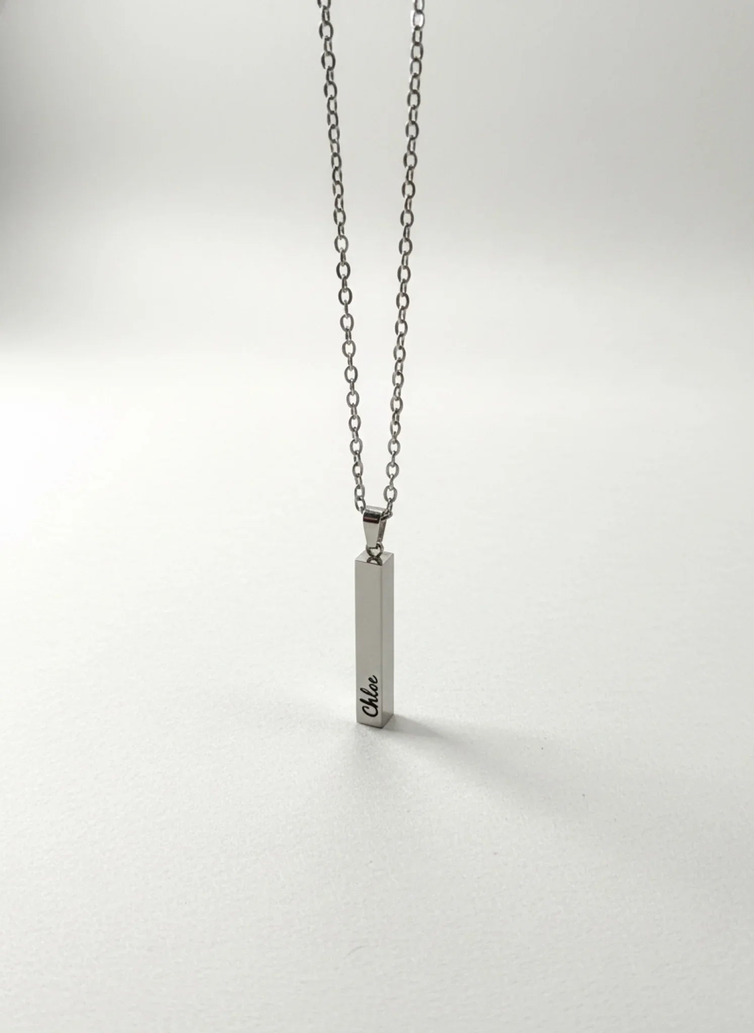 Silver chain necklace with a vertical rectangular pendant engraved with the name Chloe