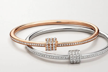 Two elegant diamond-studded bangles, one rose gold and one silver, on white background