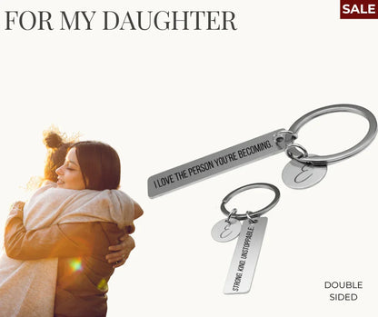 Mother and daughter hugging warmly in sunset with silver double-sided motivational keychain for daughter